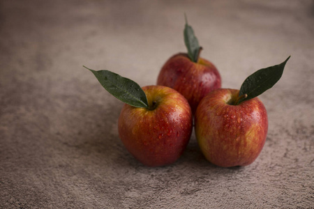  Red apples with leaves on a gray background