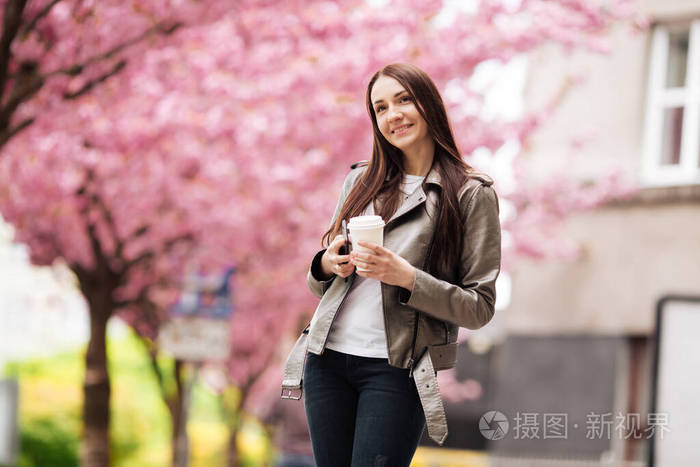 一头乌黑长发的年轻美女，在樱花盛开的樱花树旁尽情享受春天的自然之美