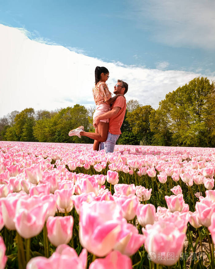 春天荷兰花圃里的男女情侣荷兰弗雷沃兰附近的橙红色郁金香园春天傍晚