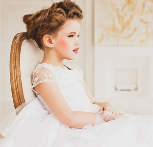一个金发的小女孩穿着白裙子。