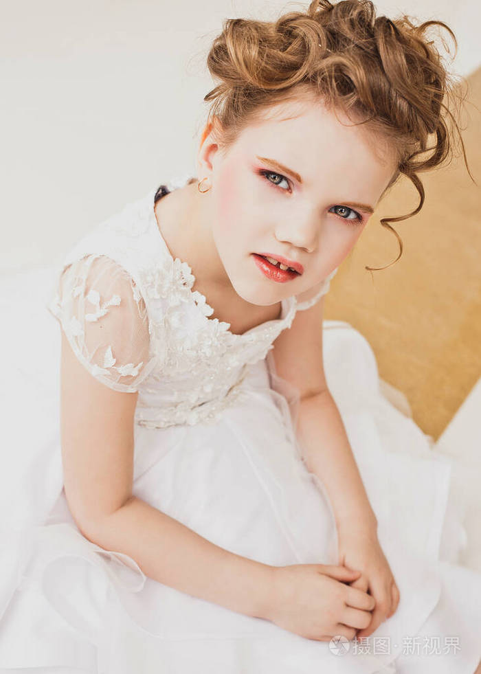 一个金发的小女孩穿着白裙子。