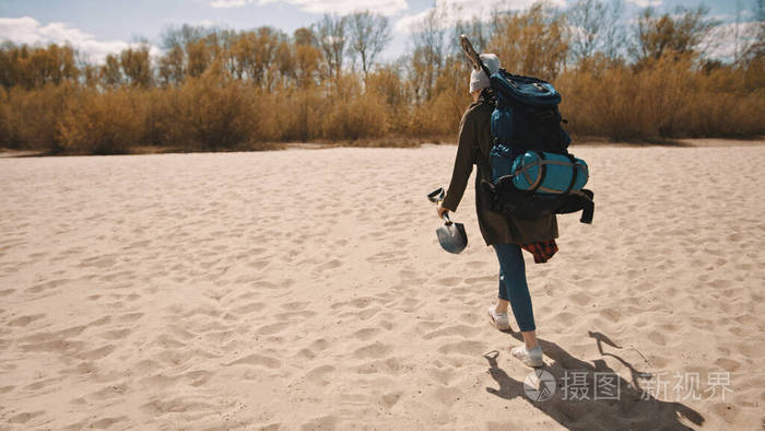 女游客的背影背包客拿着铲子在沙滩上行走复制空间