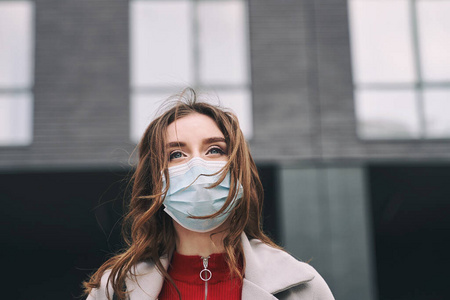 vid-19防护口罩的漂亮蓝眼睛和蓬乱头发的年轻女子满怀希望地看着上面