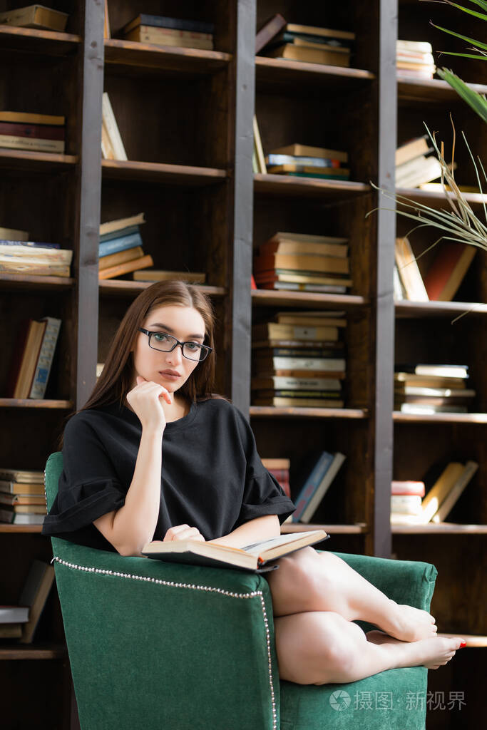 那个女人正坐在她的书房里的扶手椅上看书女孩看着镜