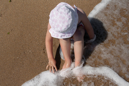 戴巴拿马帽的女孩坐在海滩上。
