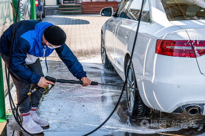 非接触式自助洗车服务年轻随意的男人在洗车
