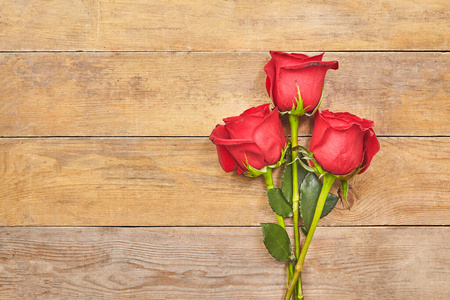 木质背景上的红玫瑰和情人节心形图案。俯视图