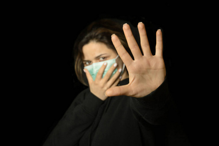 阻止病毒和流行病。戴蓝色医用防护面罩的健康女性显示停止手势。