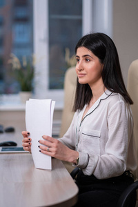 一个年轻漂亮女人的画像，一个穿着白衬衫的办公室职员。一个女人在电脑前工作。