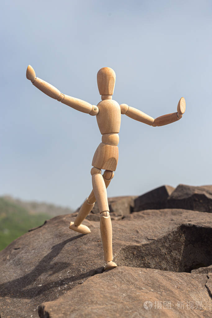 一个木头人在山上跳石头的形象.照片-正版商用图片2cwqd5-摄图新视界