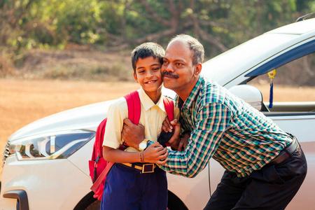 一个印度家庭在家门前开车送男孩上学