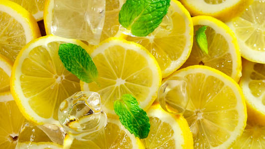 顶视图新鲜切片柠檬，薄荷和冰块旋转。闭合。