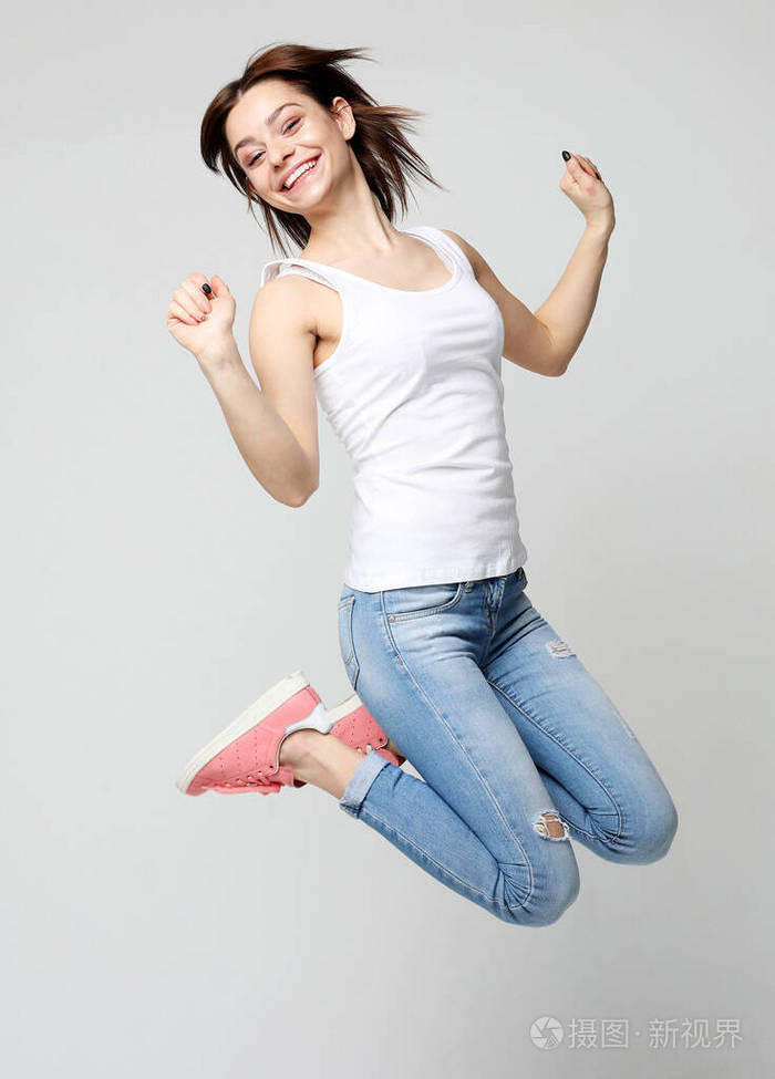 微笑的年轻女子在白色背景上跳跃