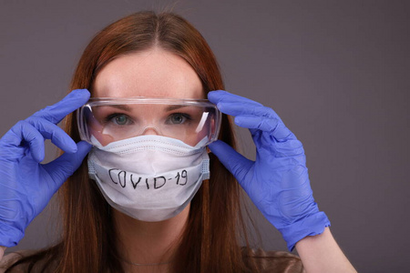 Woman in protective gloves and glasses puts on a mask coronavir