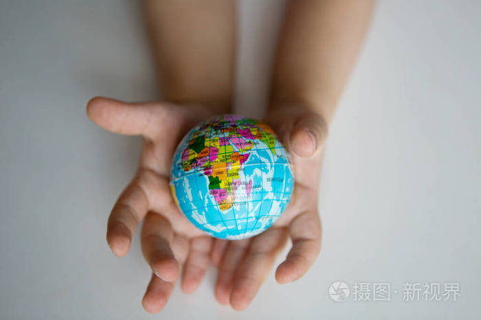在冠状病毒感染期间儿童的手拿着一个小地球仪