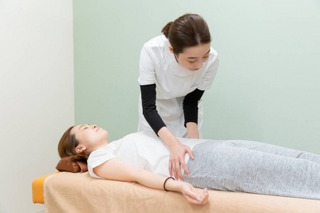 骨骼:髋骨和股骨骨干骨架上身躯干女性医生持有脊柱模型在热带 spa