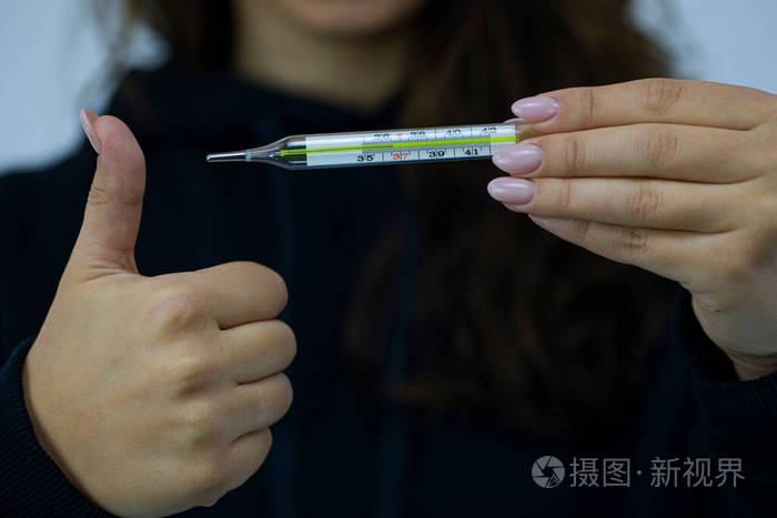 年轻女子拿着水银温度计,显示36.6度,显示出象徵状