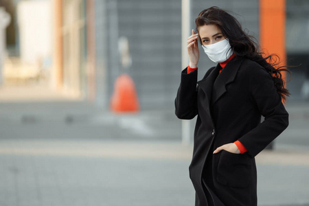 一幅美丽的妇女在街上行走的画像，戴着防护面具以防传染病。户外流感美女不开心模特
