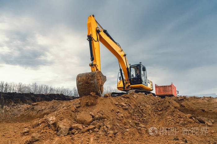 一种黄色的大型建筑挖掘机在采石场的建筑工地上工业形象