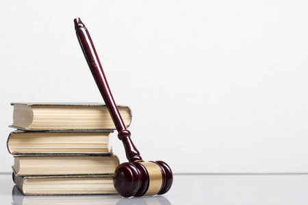 法律概念公开的法律书与木制法官木槌放在法庭或执法办公室的桌子上孤立的白色背景。复制文本空间