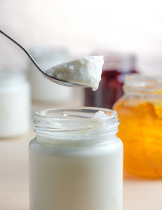 自制酸奶配橙汁汤匙,从玻璃罐里吃.健康乳制品益生菌早餐.照片