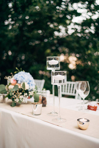 婚礼晚宴的特写镜头。蜡烛漂浮在水面上，高高的玻璃烛台上