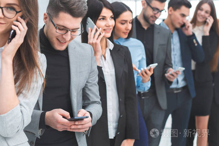 一群多元化的年轻人使用他们的智能手机