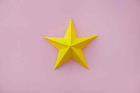 Handmade yellow paper star on pink background. 