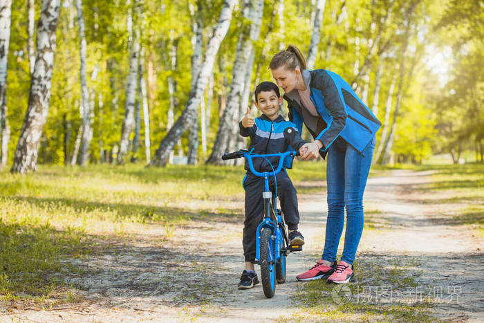 快乐的骑自行车的孩子和妈妈在阳光明媚的森林里骑自行车