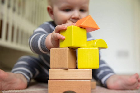 一个7个月大的婴儿推着一堆木制游戏块