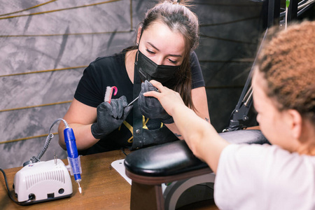 特写五金美甲.手护理的概念.女美甲师用铣刀清理指甲照片