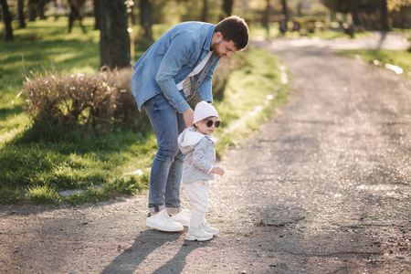 可爱的小吉尔和她父亲在一起。爸爸和女儿在公园里散步。时尚家庭。戴墨镜的快乐小女孩