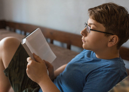 一个戴眼镜的少年在家看书。
