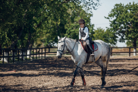 戴头盔的小女孩学骑马。马术教练。
