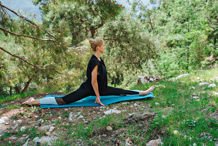 户外美景做瑜伽的女人在户外摆姿势,欣赏美丽的山林美景照片