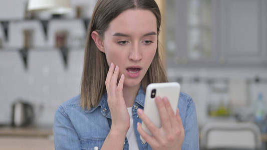 一个沮丧的年轻女人在智能手机上对失去的反应