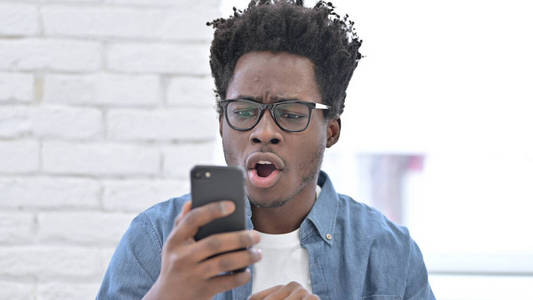 兴奋的非洲年轻人惊讶于智能手机上的好消息