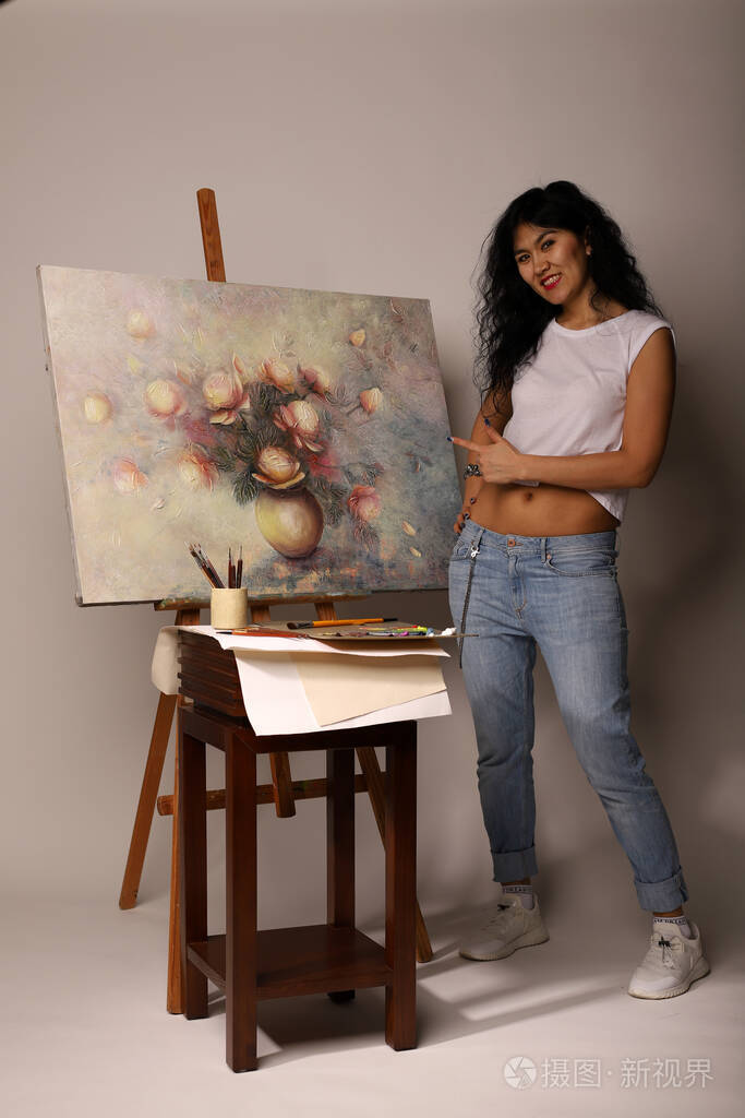 画架上的画家画了一幅画漂亮的女孩用刷子画画油画画布上花瓶里的玫瑰