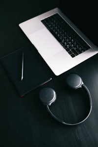 Dark modern workplace with a graphic tablet, laptop, wireless he