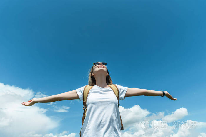 一个年轻的女孩张开双臂站在群山中对着天空自由与放松的概念