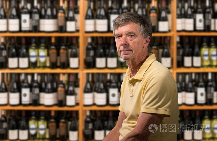 高加索老人坐在装满酒瓶的酒窖里