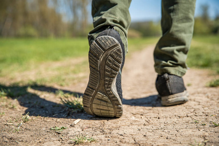 一个游客走在土路上。腿和鞋的特写