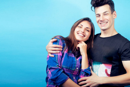 幸福的情侣在蓝色的背景下摆出欢快的姿势,男生和女生一起做朋友照片