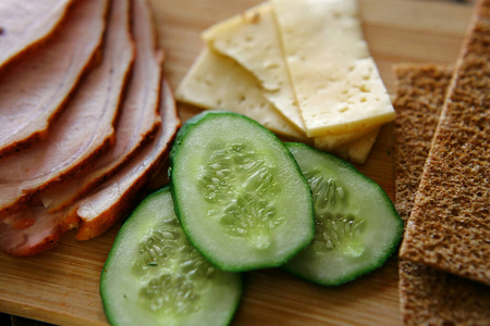 Slicing ham, cucumbers and cheese with ruddy thin breads lie on 
