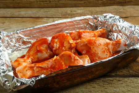 把盘用锡纸把番茄酱腌在烤盘上的鸡腿.照片
