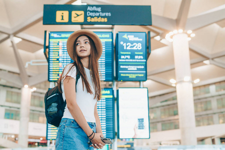 机场的一名女学生背着一顶帽子站在记分板的背景上