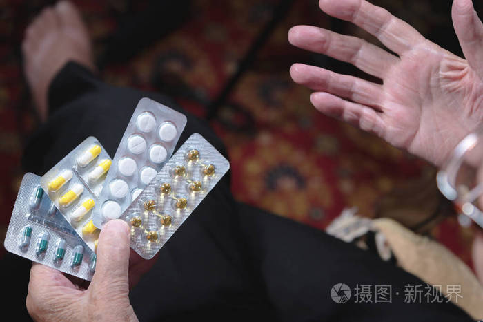 一位老妇人的特写手上拿着许多不同的药片药物选择观念与老年人的健康