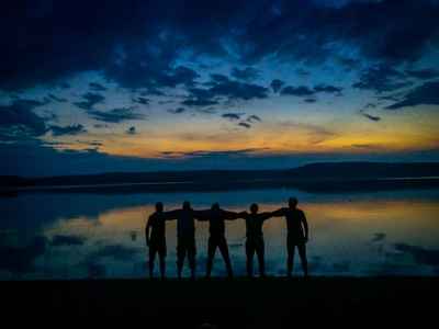 一群快乐的年轻人在海滩上欣赏美丽的夏日日落