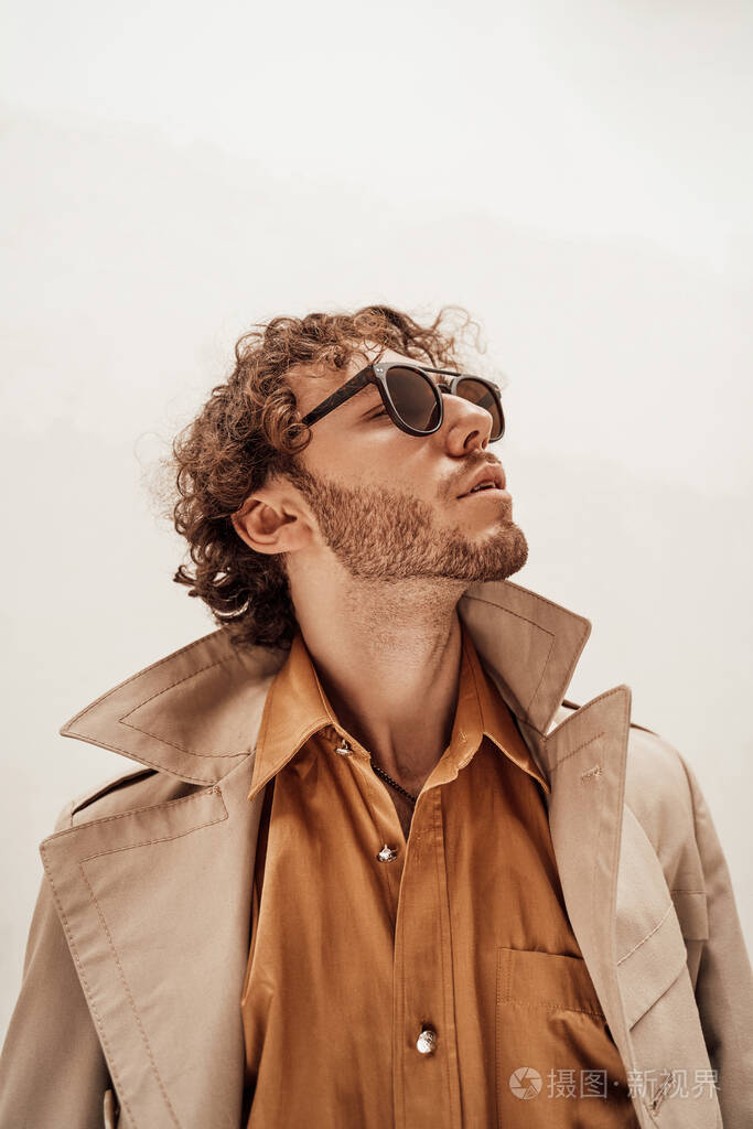 的成年男模在明亮的摄影棚里穿着酷酷的衣服站在白色的背景上抬头仰望