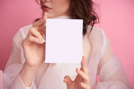  Young girl on a pink background holds an empty sheet to fill